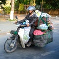 Moped rider Ho Chi Minh City or Saigon, Vietnam. Motorbike driver transporting goods and living hen on motorbike.