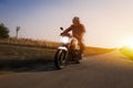Motorbike drives on the road at sun dawn