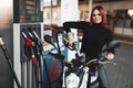 Motorbike and its female beuty owner in gas station