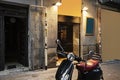 A motorbike parked on the street in front of a somewhat dirty old stone building