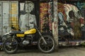 Motorbike parked on street with graffiti covered walls