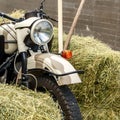 Motorbike stands amidst haystacks. Close-up. Square