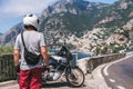 A motorbike traveler back view. On background incredibly beautiful view of Positano, a city on the edge of cliffs, the sea and a