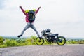 Motorbike traveler celebrating nature or after reaching destination on hill top by shouting and jumping - concept of