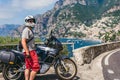 A motorbike traveler poses against the backdrop of an incredibly beautiful view of Positano, a city on the edge of cliffs, the sea