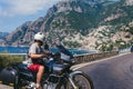 A motorbike traveler poses against the backdrop of an incredibly beautiful view of Positano, a city on the edge of cliffs, the sea