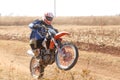 Motorbike wheelie on back wheel kicking up trail of dust on sand