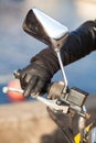 Motorbiker arm in black glove holds twist grip throttle and brake with two fingers, close-up view