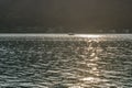 A motorboat crosses Lake Lugano at sunset, with golden reflections on the water, Porto Ceresio, Italy Royalty Free Stock Photo