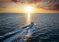 A motorboat cruising over the sea into the sunset Royalty Free Stock Photo