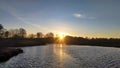 The motorboat slowly moves down the river right into the setting sun. On the banks stand leafless bushes and trees. There are slig Royalty Free Stock Photo