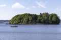 Motorboat with two people on blue water infront of a green and lush island Royalty Free Stock Photo