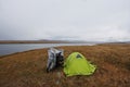 Motorcycle alone traveler near green tent at dark gloom fog steppe shore of lake Royalty Free Stock Photo