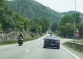Motorcycle and car in traffic. Road signs on the side of the road.