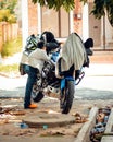 Motorcycle covered with jackets and a child using mobile phone standing near in a sunny day.