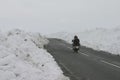 A motorcycle crossing high ground with deep snow by the road