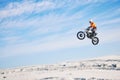 Motorcycle, desert and jump for sports in race, adrenaline and training for fitness in competition. Athlete, sky and