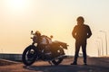 Motorcycle driver in a helmet and leather jacket stands on the road next to a sports motorcycle