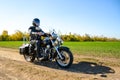 Motorcycle Driver Riding Custom Chopper Bike on Autumn Dirt Road in the Green Field. Adventure Concept. Royalty Free Stock Photo