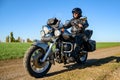 Motorcycle Driver Riding Custom Chopper Bike on Autumn Dirt Road in the Green Field. Adventure Concept. Royalty Free Stock Photo