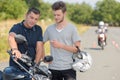 motorcycle driving instructor explaining handlebar controls to young biker Royalty Free Stock Photo