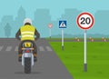 Learner motorcyclist practising to ride a moto. Back view of a student biker on test road with traffic signs.