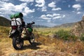 Motorcycle enduro traveler with suitcases in mountain valley on the background of the rocky hills