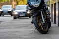 A motorcycle parked on the sidewalk with a defocused city street with cars in the background Royalty Free Stock Photo