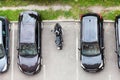 Motorcycle is parked on vehicle parking space between several cars. Top view