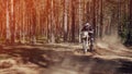 motorcycle racer on an enduro sports motorcycle rides fast on a dusty road in the forest in an off-road race