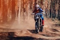 motorcycle racer on an enduro sports motorcycle rides fast on a dusty road in the forest in an off-road race