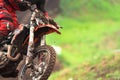 Motorcycle racing in the rain. The front wheel and handlebar of the motorcycle with the rider`s body part in the dirt. Selective