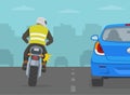 Motorcycle rider is trying to overtake the car from the left side. Back view.