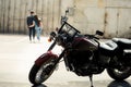 Motorcycle standing on pavement and young couple walking behind