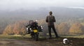 Motorcycle and standing rider in an autumn valley.