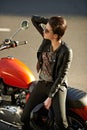 Motorcycle, street and woman in city with sunglasses for travel, transport or road trip as rebel. Fashion, leather and Royalty Free Stock Photo