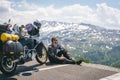 A motorcycle traveler is sitting with his touring motorbike and lokk at distance. Copy space. Conquering the top of the mountain,