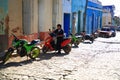 Motorcycles are parked alongside houses on a bright sunny day. Trinidad, Cuba