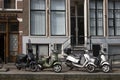 Motorcycles and scooters parked near the traditional Amsterdam house
