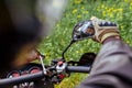 Motorcyclist looking in mirror of motobike outdoors. Man in leather jacket and helmet ride in summer forest Royalty Free Stock Photo