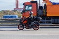 Motorcyclist in a helmet on a motorcycle, on the road, against the background of an orange truck