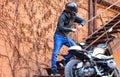 Motorcyclist with helmet near parked motorcycle.