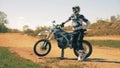 Motorcyclist and his autobike are standing in the middle of a dusty landscape