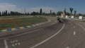 Motorcyclist leaves the parking area on a race track, circle, behind black bike.