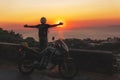 Motorcyclist man enjoy beautiful sunset arms spread out to the sides, sea and mountains. Destination. Motorcycle tour journey. Royalty Free Stock Photo