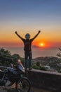 Motorcyclist man enjoy beautiful sunset arms spread out to the sides, sea and mountains. Destination. Motorcycle tour journey. Royalty Free Stock Photo