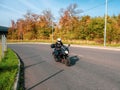 Motorcyclist in motion. Woman biker on a black motorcycle in traffic on a rural autumn road Royalty Free Stock Photo