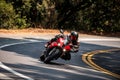 Motorcyclist on a red sports bike riding fast through a left-hand turn on a twisty road
