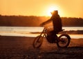 Motorcyclist`s silhouette on e-motorbike at sunset
