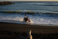 Motorcyclist speeding along waterline on CAstlecliff beach at dusk